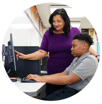 GreenTree Preparatory Academy teacher helping a student at a computer.